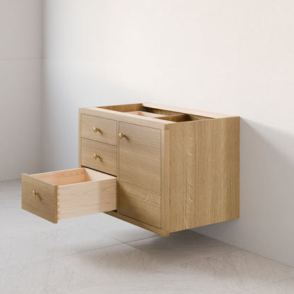 A Krovel Furniture Co. Single Door, Triple Drawer Vanity in White Oak with brass handles is mounted on a light wall. It includes one closed cabinet door and three soft-close drawers over a tiled floor.