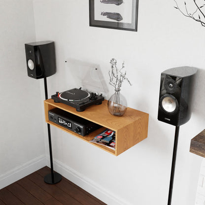 The sleek audio setup proudly features a turntable, amplifier, and speakers elegantly arranged on Krovel's Stereo Table in Cherry. This mid-century modern piece also accommodates magazines on its wooden shelf and showcases a vase of dried flowers. The space is adorned with light-colored walls and highlighted by a framed art piece.