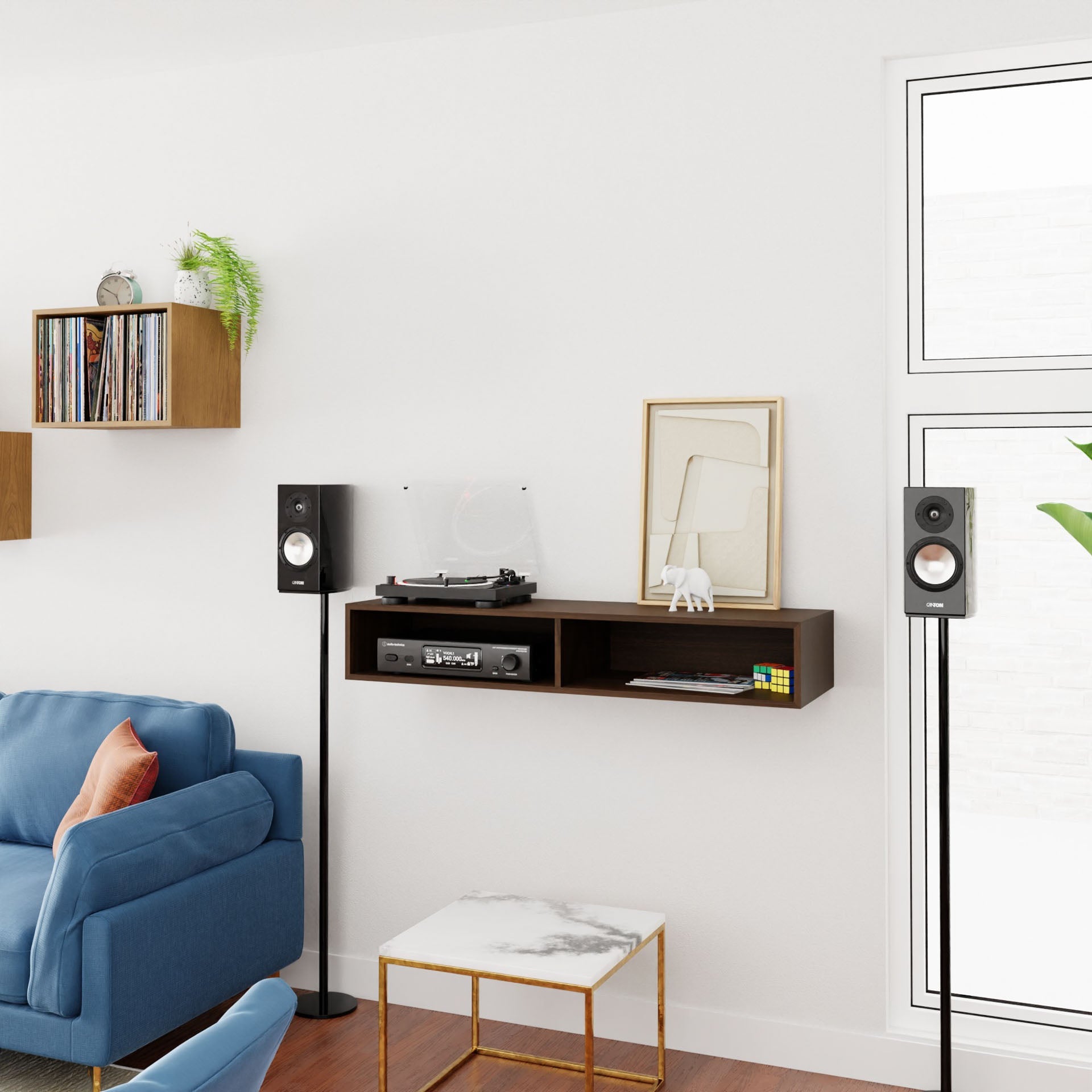 A modern living room showcases a blue sofa, a small white marble coffee table, and Krovel's Stereo Table in Walnut, adorned with a turntable, records, and a Rubik’s cube. Two speakers on sleek poles enhance the mid-century modern ambiance as natural light streams through a large window. Plants and art add the finishing touches to the decor.