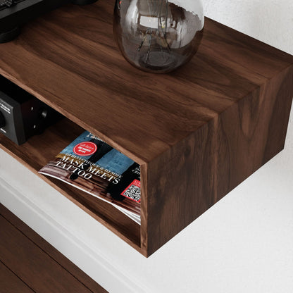 A mid-century modern wooden wall-mounted shelf holds a transparent vase and a glossy magazine featuring "Tattoo" on its cover. The magazine is partially visible, neatly tucked inside the open-ended shelf. The floor beneath is crafted from an exquisite Krovel Stereo Table in Walnut, beautifully complementing the aesthetic.